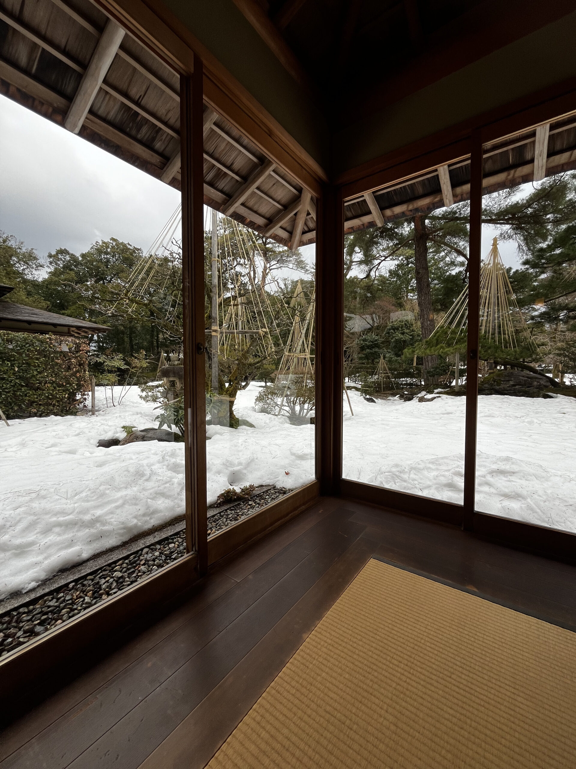 Shigure-tei teahouse interior at Kenrokuen Garden Kanazawa — view of snow-covered garden with yukizuri ropes
